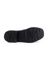 Black rubber shoe sole with textured treads, featuring a wide, rounded toe and pronounced grooves for traction.