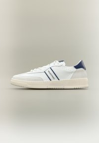 Bílá kožená teniska s námořnicky modr�ými detaily, vybavená texturovanou špičkou, perforovanými prvky a robustní gumovou podešví. Logo na boku.