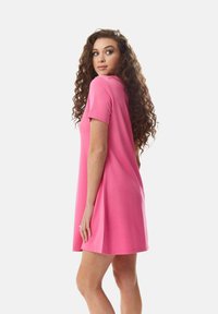 Short pink dress with short sleeves, A-line shape, made of smooth fabric. Features a rounded neckline and a loose fit around the hips.