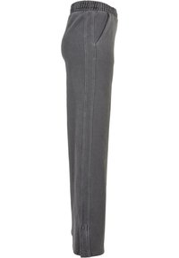Pantalon de survêtement gris avec une ceinture élastique, des poches latérales et une coupe fuselée. Le tissu a une texture douce et un design décontracté.