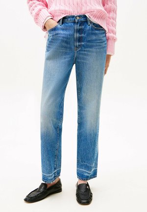 Jeans in denim blu con taglio dritto, dotati di vita alta, due tasche frontali e un finish sbiadito. Mocassini neri indossati come calzature.