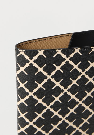 Κοντινή λήψη ενός δερμάτινου αντικειμένου σε μαύρο και μπεζ χρώμα με επαναλαμβανόμενο γεωμετρικό πλέγμα και ορατή καφέ υφασμάτινη επένδυση εσωτερικά.