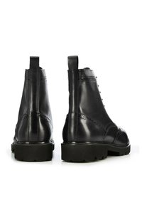 Botas de tobillo de piel negra con un diseño elegante, que cuentan con una textura suave, acentos de costuras elevadas y una suela de goma gruesa.
