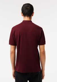 Polo en bourgogne à manches courtes, vue arrière montrant une texture lisse, col classique et un ourlet droit sans ornements.