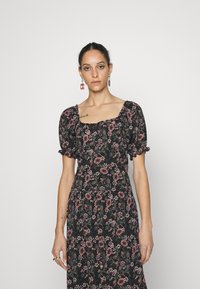 Vestido preto florido com mangas bufantes, decote quadrado e padrões florais rosas. Apresenta um corpete justo e botões ao longo da saia.