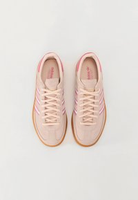 Lys rosa suede sneakers har tre rosa striper på sidene, en såle av gummigummi og en polstret krage for komfort.