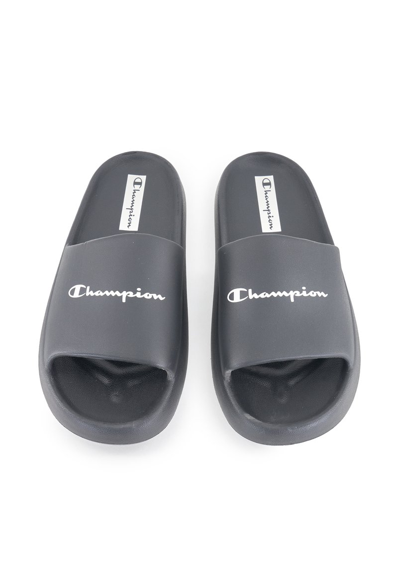 Sandali in gomma nera con design open toe, caratterizzati da una fascia larga e la scritta "Champion" in lettere bianche sulla parte anteriore.