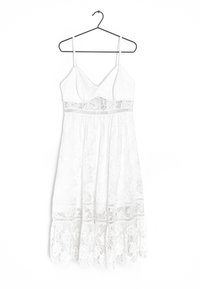 Vestido blanco de encaje con tirantes finos, escote en V, corsé ajustado y falda en capas con motivos florales y acentos de encaje.