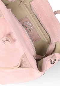 Sac en suede rose clair avec une double fermeture éclair, doublure intérieure beige et une étiquette en cuir avec l'imprimé "Fabriqué en Italie".