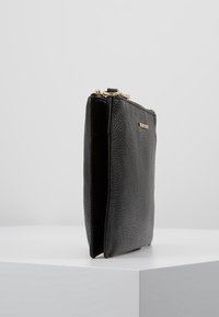 Sort læder clutch taske med en struktureret overflade, der har en gylden lynlåslukning og en slank profil.