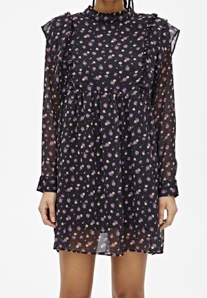 Robe noire à fleurs avec des manches courtes, des détails froncés et un tissu transparent. Petites fleurs violettes et jaunes réparties sur l'ensemble. Design sans col.