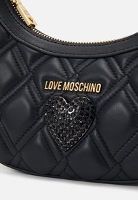 Black quilted faux leather bag featuring a gold "LOVE MOSCHINO" emblem and a black rhinestone heart detail. Accented with gold hardware.