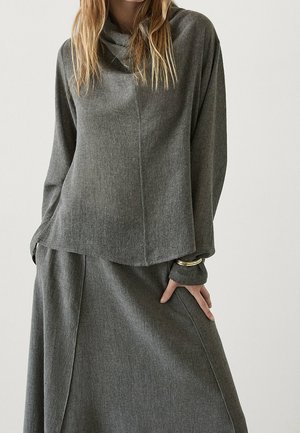 Gray, miękki sweter z dekoltem w łódkę i długimi rękawami, w połączeniu z pasującą spódnicą z bocznymi kieszeniami i subtelnym drapowaniem.