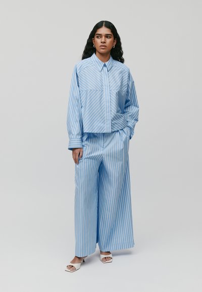 Lichtblauwe gestreepte shirt met een kraag, gecombineerd met bijpassende wijde broek in hetzelfde patroon. Gladde stof, minimale details.