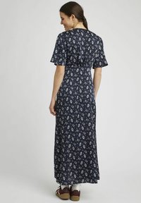Robe maxi à imprimé floral marine avec des manches courtes évasées et une taille ajustée. Fabriquée dans un tissu léger avec de délicats motifs blancs.