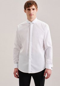 Camicia bianca a maniche lunghe con bottoni realizzata in tessuto liscio, dotata di colletto strutturato, pattina discreta e dettagli a contrasto sui polsini.