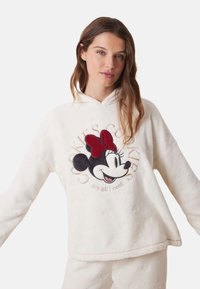Hvid fleece hoodie med et broderet Minnie Mouse-design med en rød sløjfe, omgivet af teksten "Kager er alt, jeg har brug for."