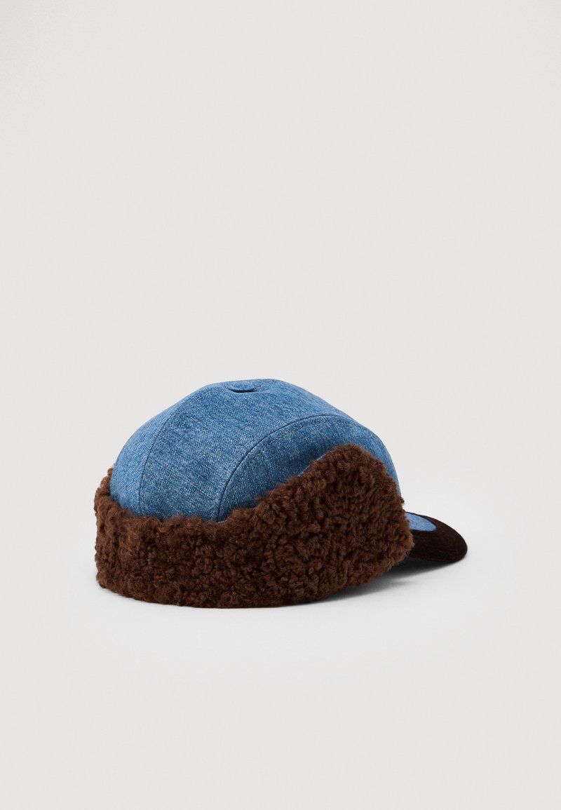 Blue denim cap with a brown fuzzy fleece lining around the base and a small eyelet on top, resting on a white background.