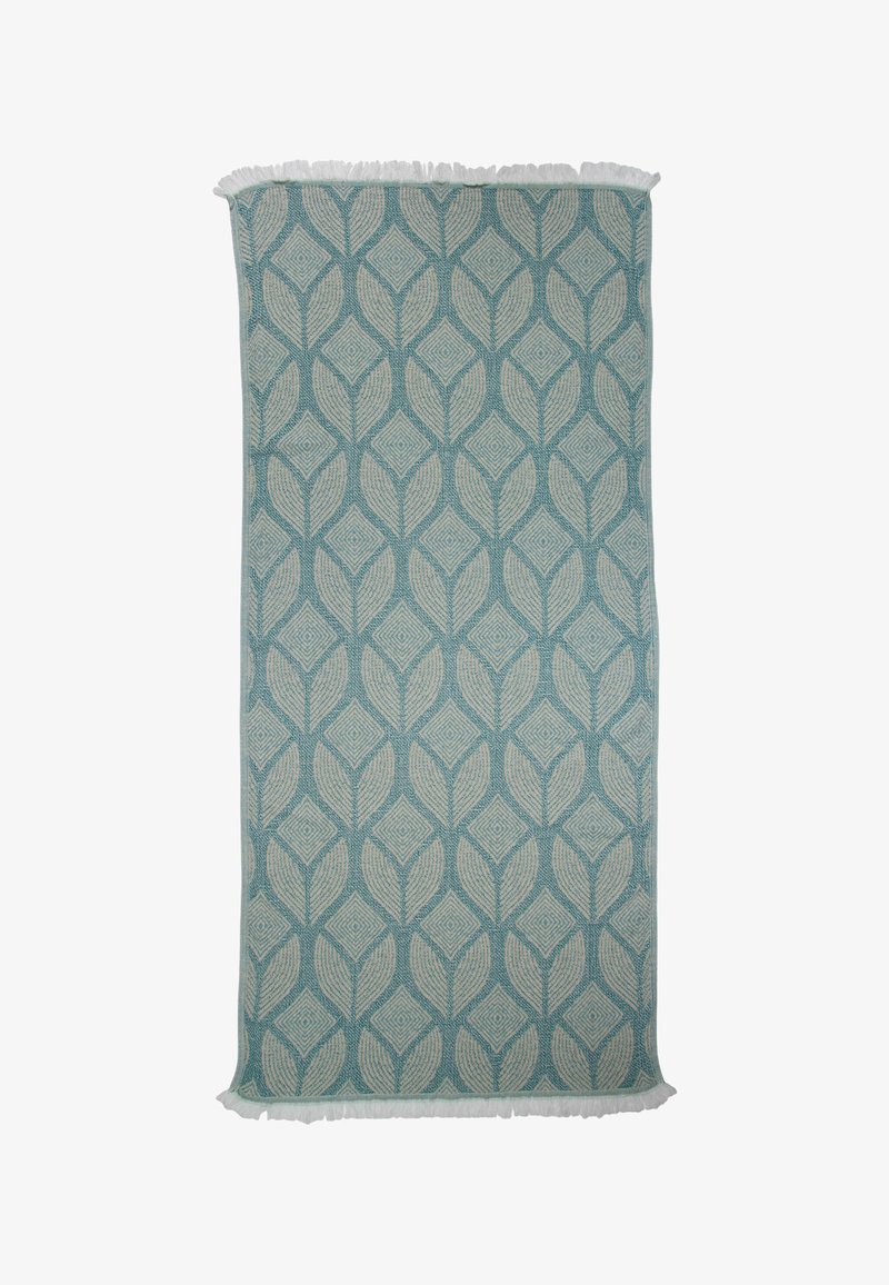 Lichtblauwe geweven dekentje met een bladerenpatroon in beige, met franje randen. Rectangulaire vorm met een gestructureerd oppervlak.