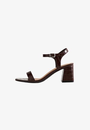 Bruine leren blokhak sandalen met enkelbandje en zilveren gesp, voorzien van een gestructureerd krokodillenpatroon en open teen ontwerp.