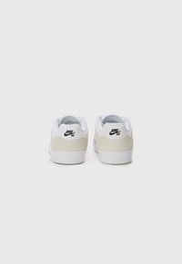 Nike SB tenisice s gornjim dijelom od bijele kože, bež nubuk naglascima i bijelim gumennim potplatom. Crni logo na peti upotpunjuje dizajn.