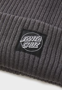 Berretto a coste grigio con un'etichetta quadrata nera con il logo "SANTA CRUZ" ricamato in un design circolare sul davanti.