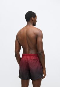 Ανδρικά μαγιό βερμούδα σε βαθμιαία μετάβαση από κόκκινο σε μαύρο, με ελαστική μέση και μία πίσω τσέπη. Λείο, ελαφρύ υλικό.