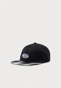 Casquette noire avec un bord à motif pied-de-poule gris et noir, arborant un logo ovale blanc avec le mot "Billabong" sur le devant. Matériau en coton, design à six panneaux.