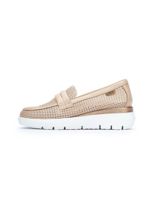 Zapato deslizante de cuero beige con diseño perforado, detalle de correa a juego y una suela blanca con ranuras para agarre y comodidad.