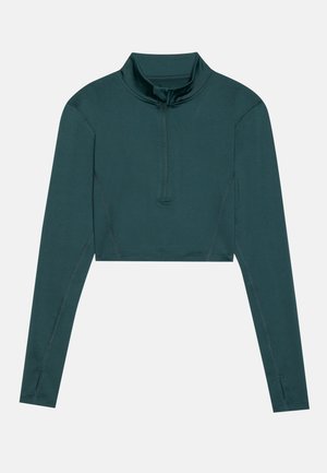 Top corto en azul verdoso oscuro, de mangas largas, cuello alto con media cremallera, textura suave, costuras reforzadas.