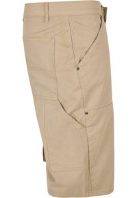 Beige cargo šortky vyrobené z bavlny. Mají více kapes, volný střih a kontrastní šití podél švů.
