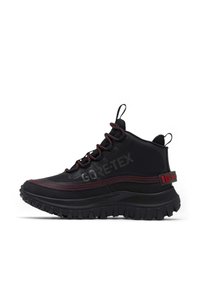 Chaussures de randonnée noires mi-hautes avec logo Gore-Tex, présentant des accents rouges, une semelle en caoutchouc texturée et des détails de couture contrastants.