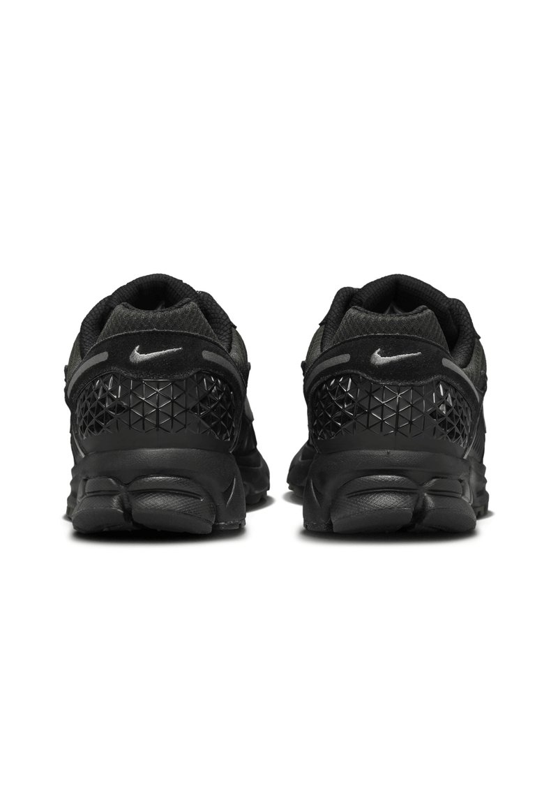 Des baskets Nike noires avec un motif géométrique texturé sur le talon et une semelle rembourrée pour le confort. Le design est épuré et moderne.