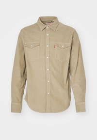 Chemise beige en velours côtelé à manches longues avec boutons-pression, col pointu et deux poches avant à rabat avec fermeture par bouton.