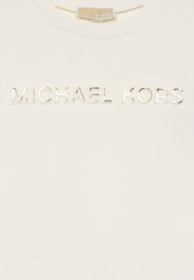 T-shirt couleur crème avec un logo "MICHAEL KORS" en or métallique en relief centré sur la poitrine. Tissu lisse avec un col rond.