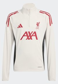 Vit långärmad Liverpool FC träningsjacka med röda logotyper, halvzipkrage, röda axelränder och svarta sidor.