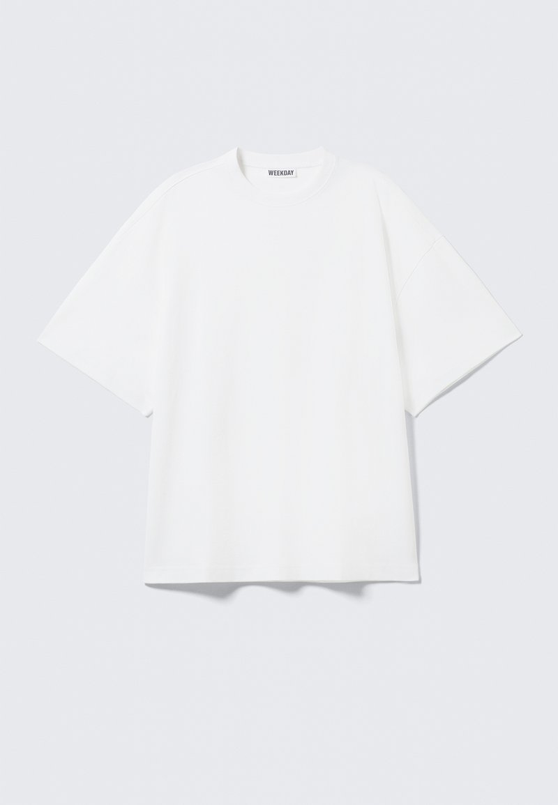 Λευκό βαμβακερό T-shirt με κοντά μανίκια, άνετη εφαρμογή, στρογγυλή λαιμόκοψη και χωρίς ορατά σχέδια ή διακοσμητικά στοιχεία.