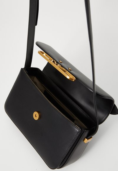 Borsa a spalla in pelle nera con chiusura e parte metallica dorate, caratterizzata da un design strutturato, una singola tracolla e un interno aperto.