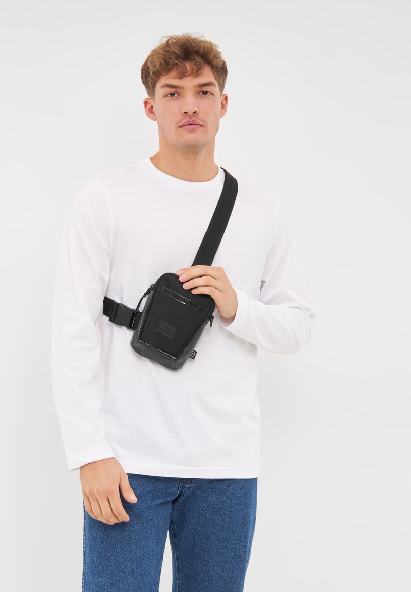 Borsa a tracolla nera realizzata in materiale resistente, con una parte anteriore texture, tasca con zip e tracolla regolabile. Design rettangolare compatto.