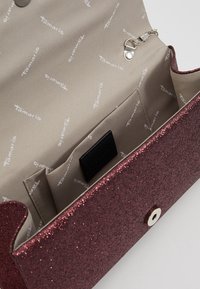 Błyszczący bordowy portfel wykonany z materiału syntetycznego, z beżowym wnętrzem z powtarzającym się logo „Tamaris” oraz czarną kieszonką na karty.