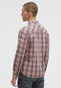 Herren-Hemd mit Karomuster in verschiedenen Rosa- und Blautönen, mit langen Ärmeln, Knopfmanschetten und einem kleinen Logo-Detail auf dem Rücken. Leichtes Material.