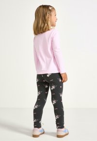 Lyserød langærmet top parret med mørkegrå leggings, der har et legende panda-mønster og lyserøde stjerneaccentuer. Designet til komfort.