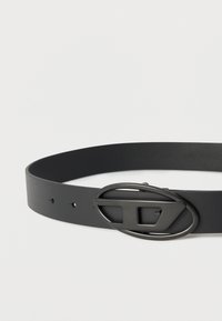 Μαύρη δερμάτινη ζώνη με λεία επιφάνεια, διαθέτει ξεχωριστή οβάλ αγκράφα από μαύρο μέταλλο. Οκτώ τρύπες για ρύθμιση.