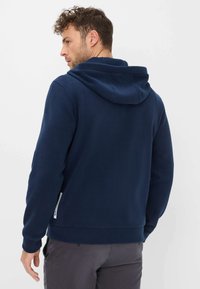 Felpa con cappuccio blu navy con tessuto strutturato, cappuccio regolabile con coulisse e tasca laterale con zip. Caratterizzata da una silhouette aderente e polsini a costine.