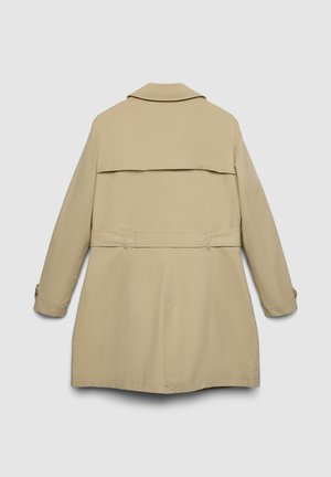 Trench-coat beige avec un détail cape au dos, manches longues et taille ceinturée. Tissu lisse avec des coutures minimales et sans quincaillerie visible.