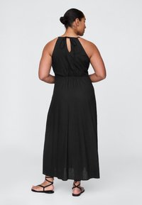 Schwarzes Maxikleid mit Neckholder und Schlüsselloch-Ausschnitt am Rücken. Der Stoff wirkt leicht und fließend, mit einer taillierten Passform zur Betonung der Silhouette.