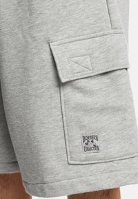 Grijze fleece shorts met een zijvak en een logo-onderscheiding. De stof is zacht met een gladde textuur en heeft een ontspannen pasvorm.