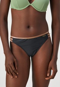 Black bikini bottoms with a smooth fabric, featuring gold-tone side straps. The design includes a low-rise cut and minimal detailing.
