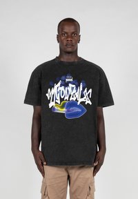 Camiseta gráfica negra con letras blancas y azules y un gráfico estilizado de labios. Diseño de manga corta y ajuste relajado.