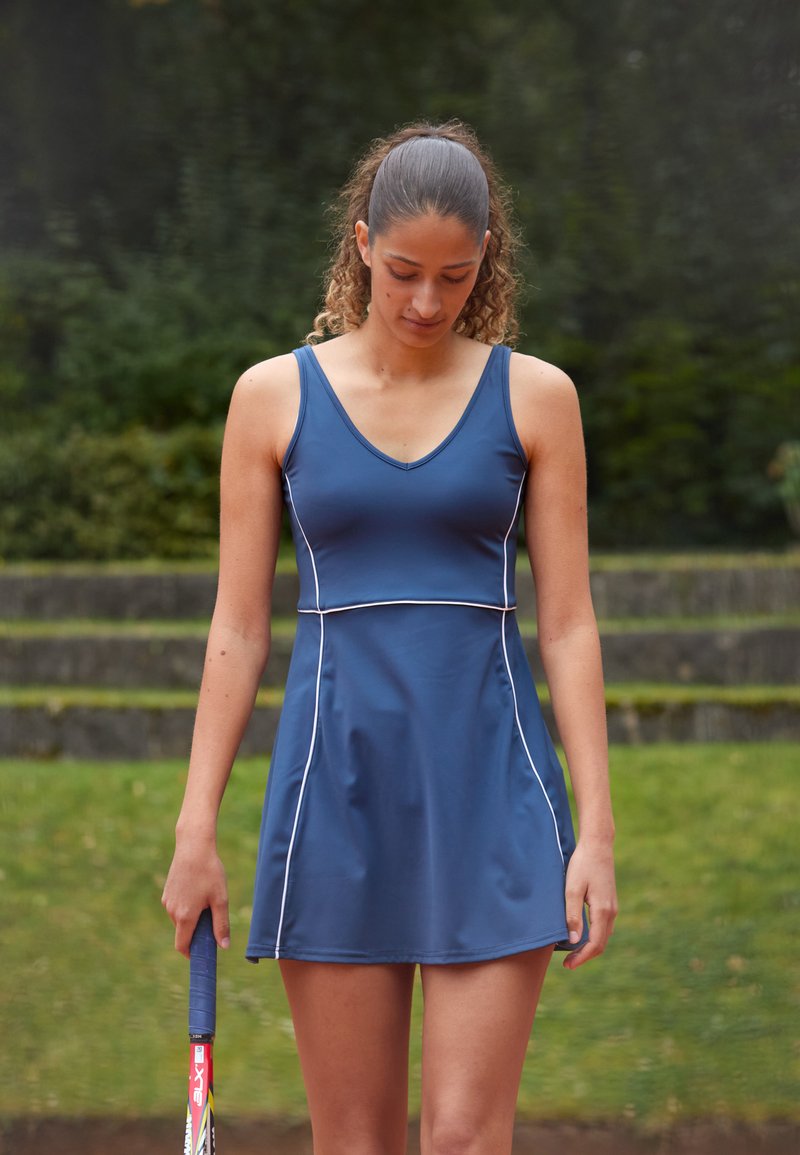 Vestido de ténis azul-marinho com corpete ajustado, saia rodada e detalhes em branco. Textura suave, desenho sem mangas e decote em V.